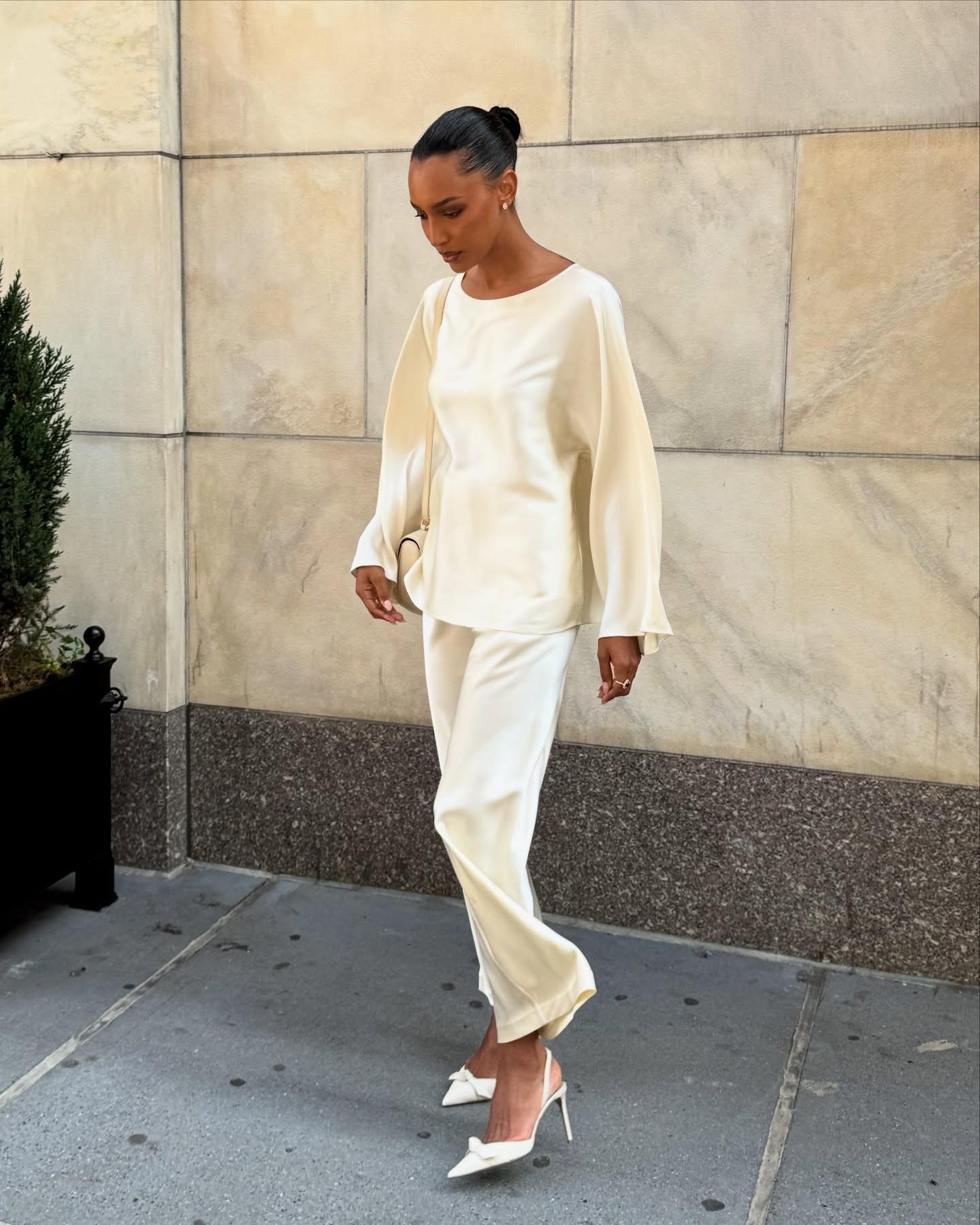 Jasmine Tookes wears a silk top, silk skirt, and white heels.