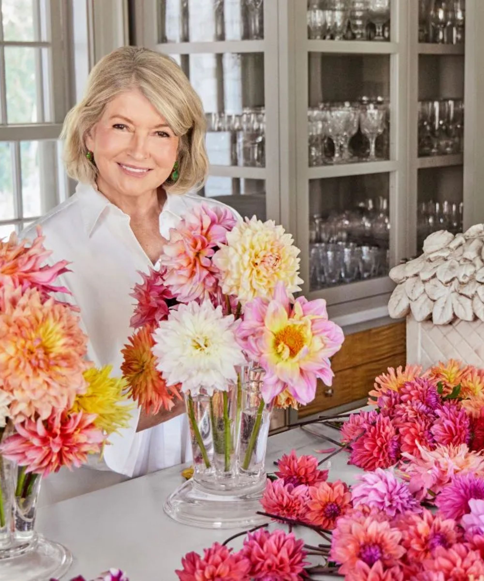 Martha Stewart behind a kitchen island covered with vases of pink flowers