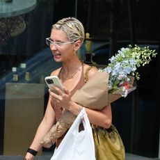 Iris Law wearing a brown tank top, white genie pants, and pink Miu Miu satin flats