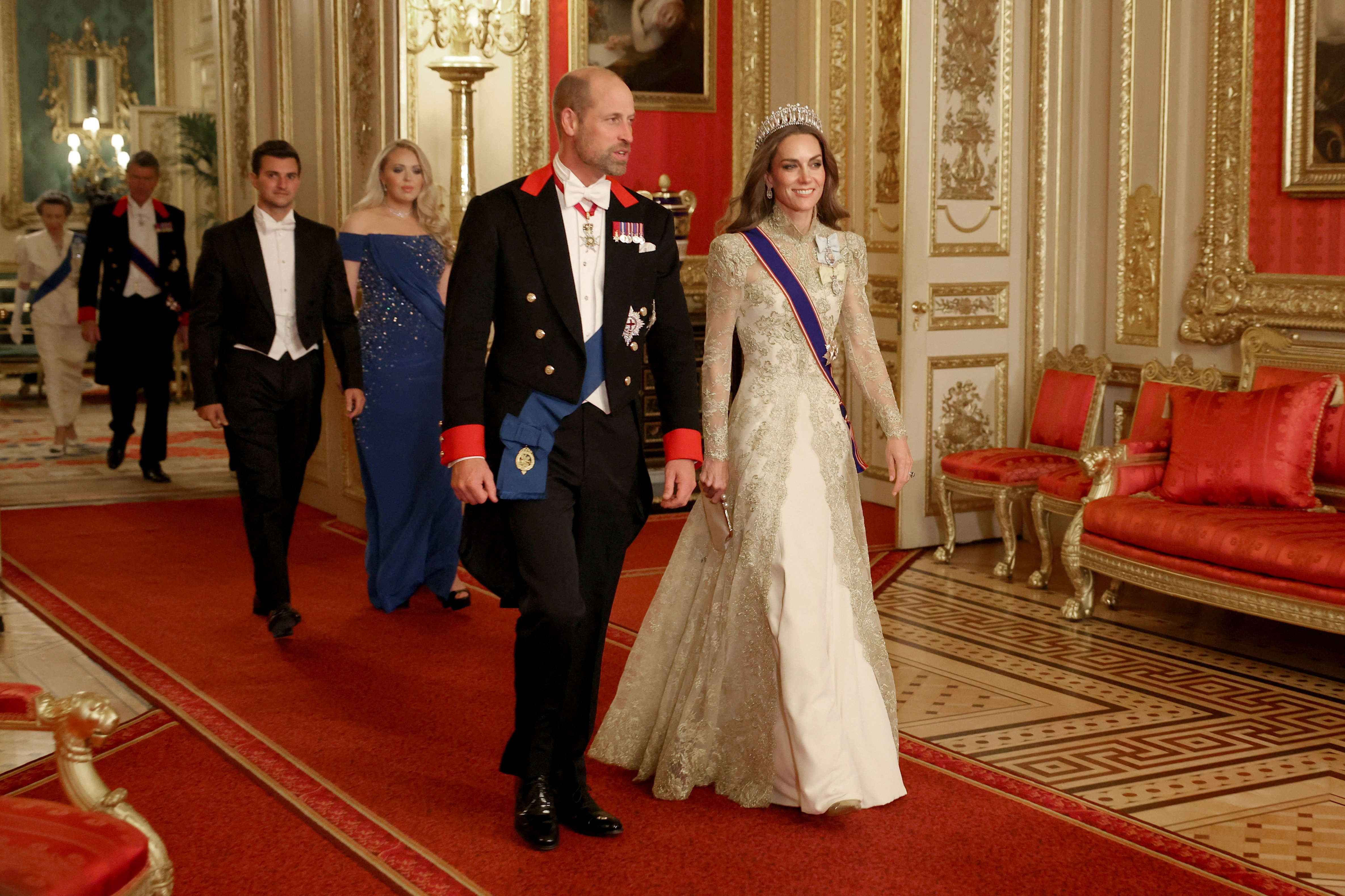 Princess Kate wearing a gold gown walking with Prince William at a state banquet