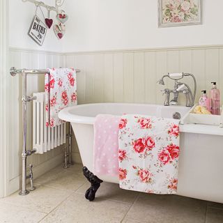 Bathroom with white bathtub and bright pink rose patterned towels