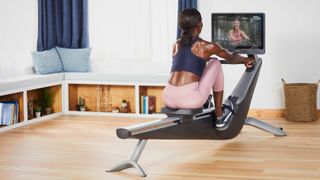 Attractive woman in sports outfit using the Hydrow connected rower in a living room