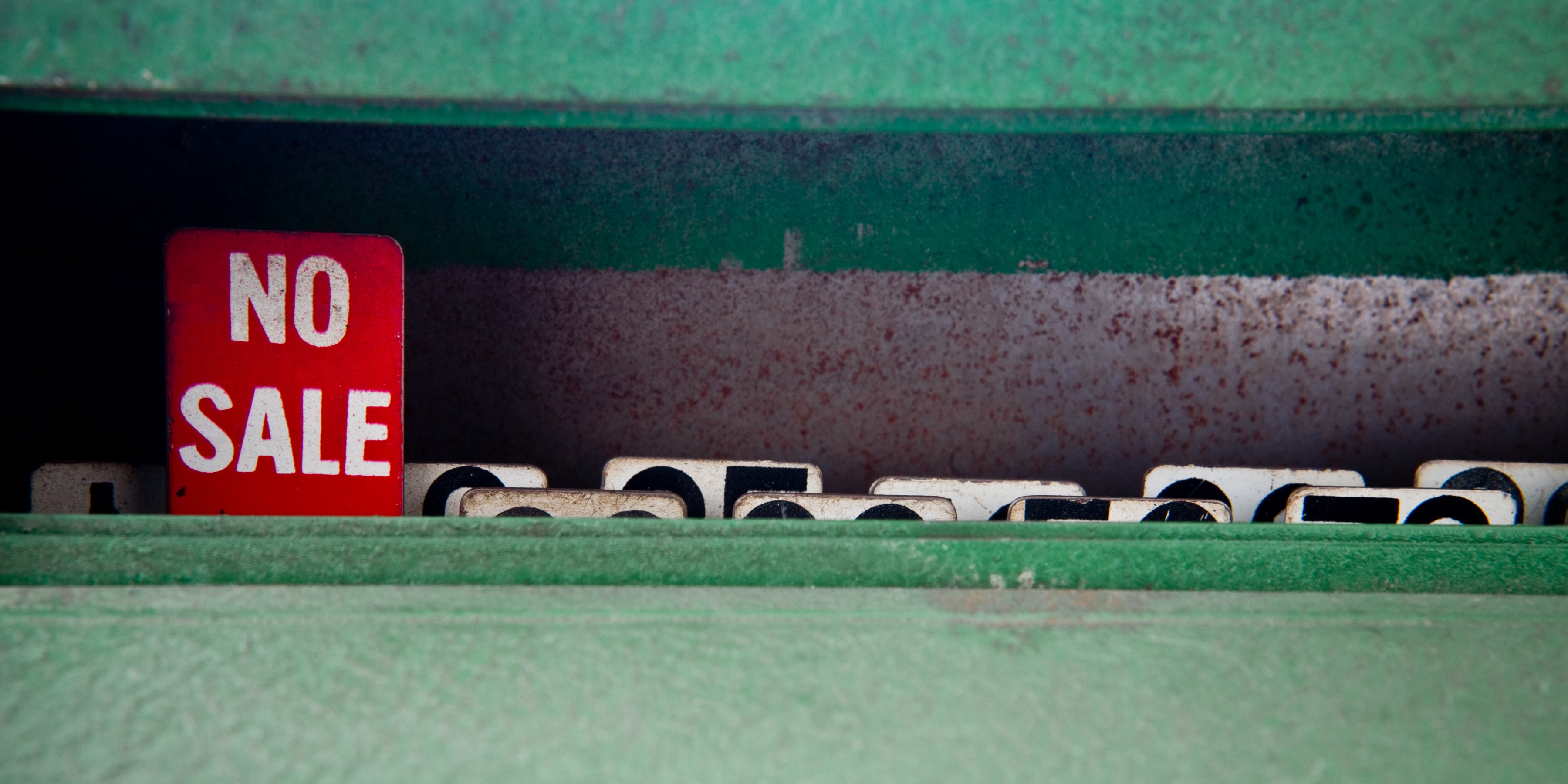 Red no sale sign popping up out of green files in cabinet