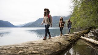 Three women crossing a log in the Pacific Northwest