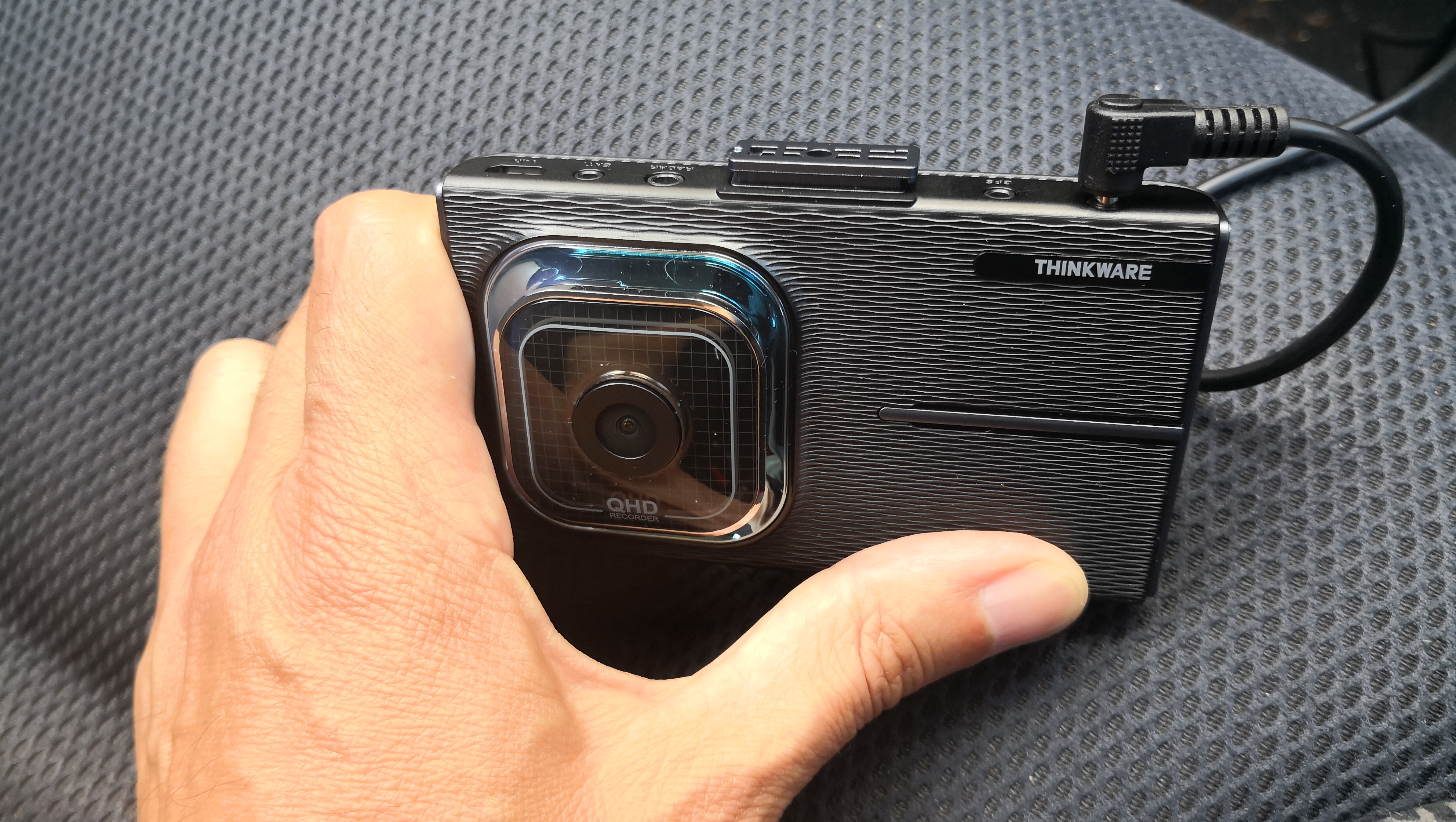 The Thinkware X1000 dash cam sitting on a car seat