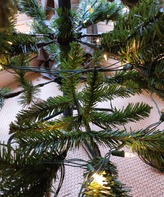close up of fake christmas tree with lights with branches spread out according to tiktok hack