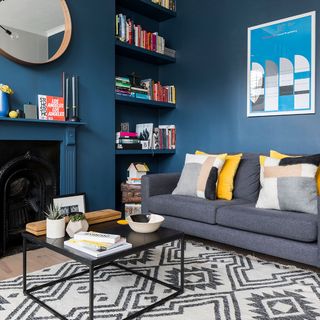 living room with blue wall book shelf and grey sofa with cushion