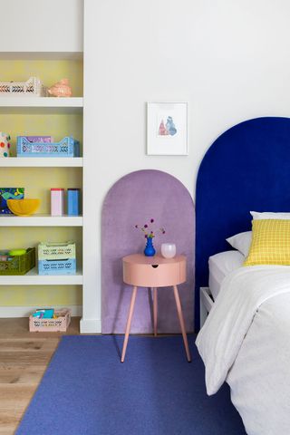 child's bedroom with bright colors and blue bedhead with open shelves