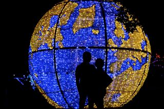 A couple silhouetted against a large lit-up globe