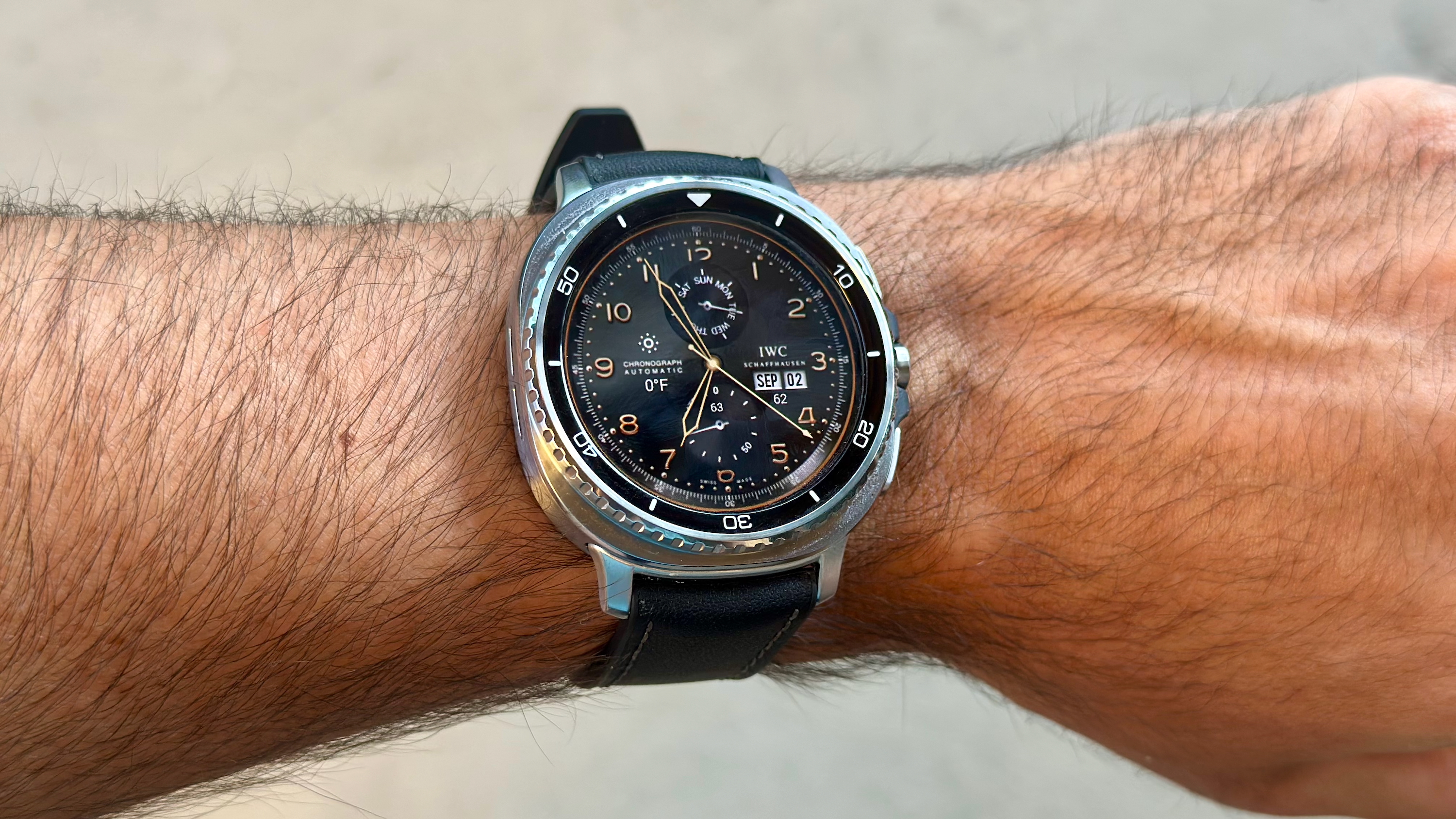 The Samsung Galaxy Watch 8 Classic on a person's wrist, showing a custom watch face from TIMEFLIK, imitating a classic Schaffhauser watch.