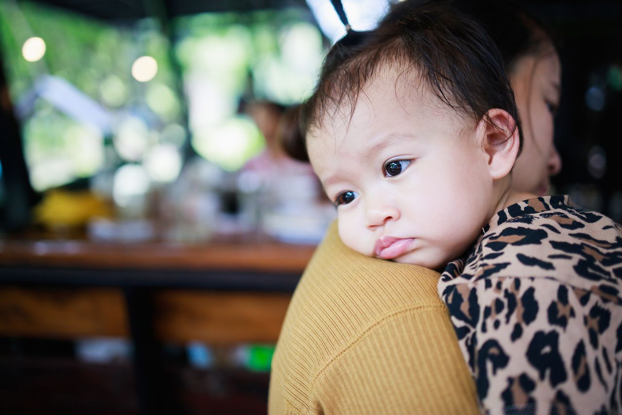 A tired baby rests his head on his mother&#039;s shoulder