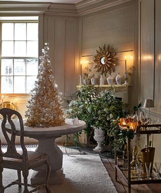 Christmas decorating ideas, Christmas Tree on a table and a flower arrangement in front of a fireplace.