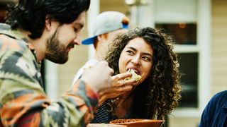 Medium close up shot of woman eating tacos with friends at food truck.