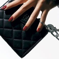 hand with lace sleeve holding a chanel wallet