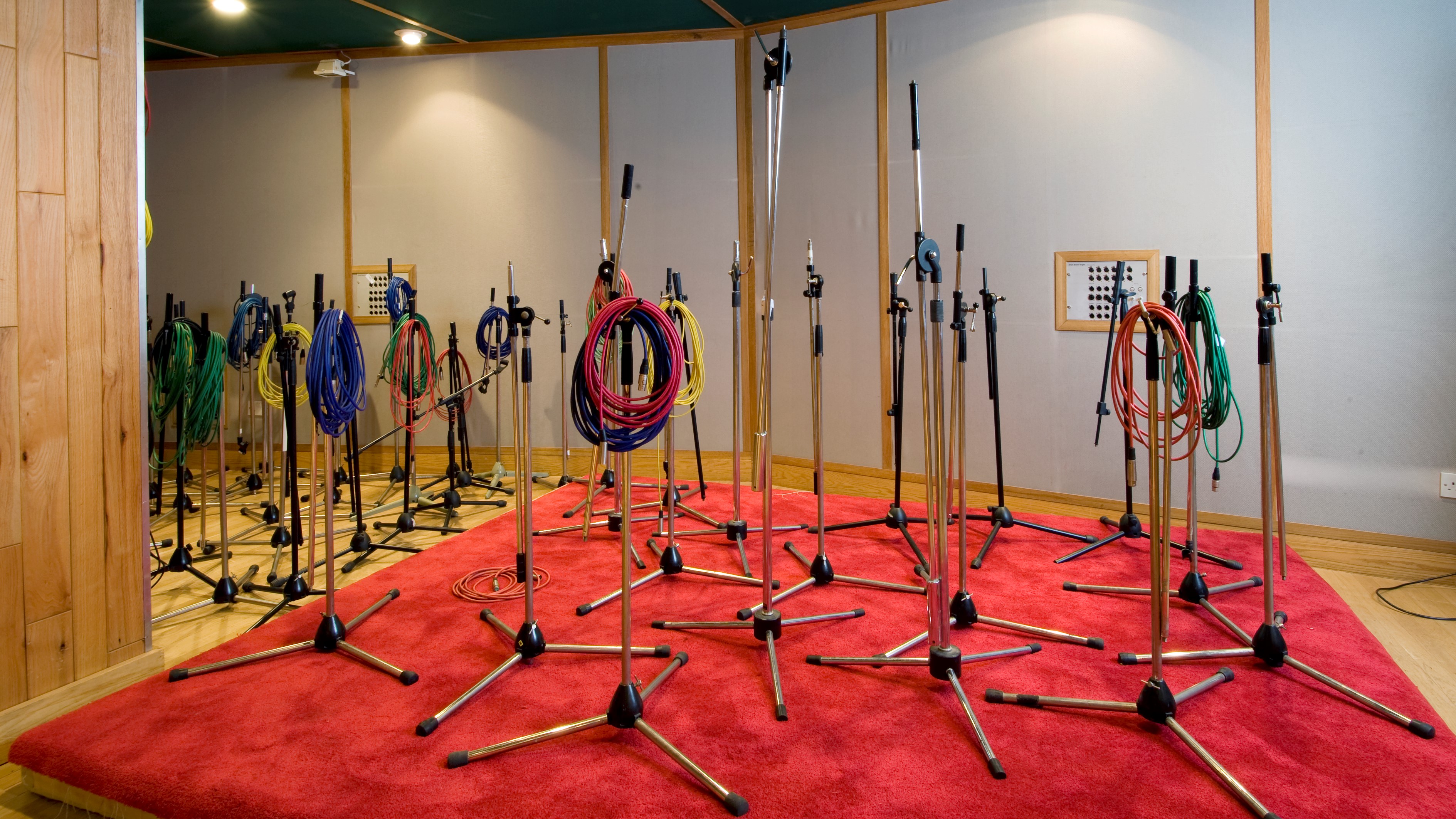 Various microphone stands set up in a studio on a red carpet