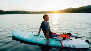 man sat on paddle board with dog