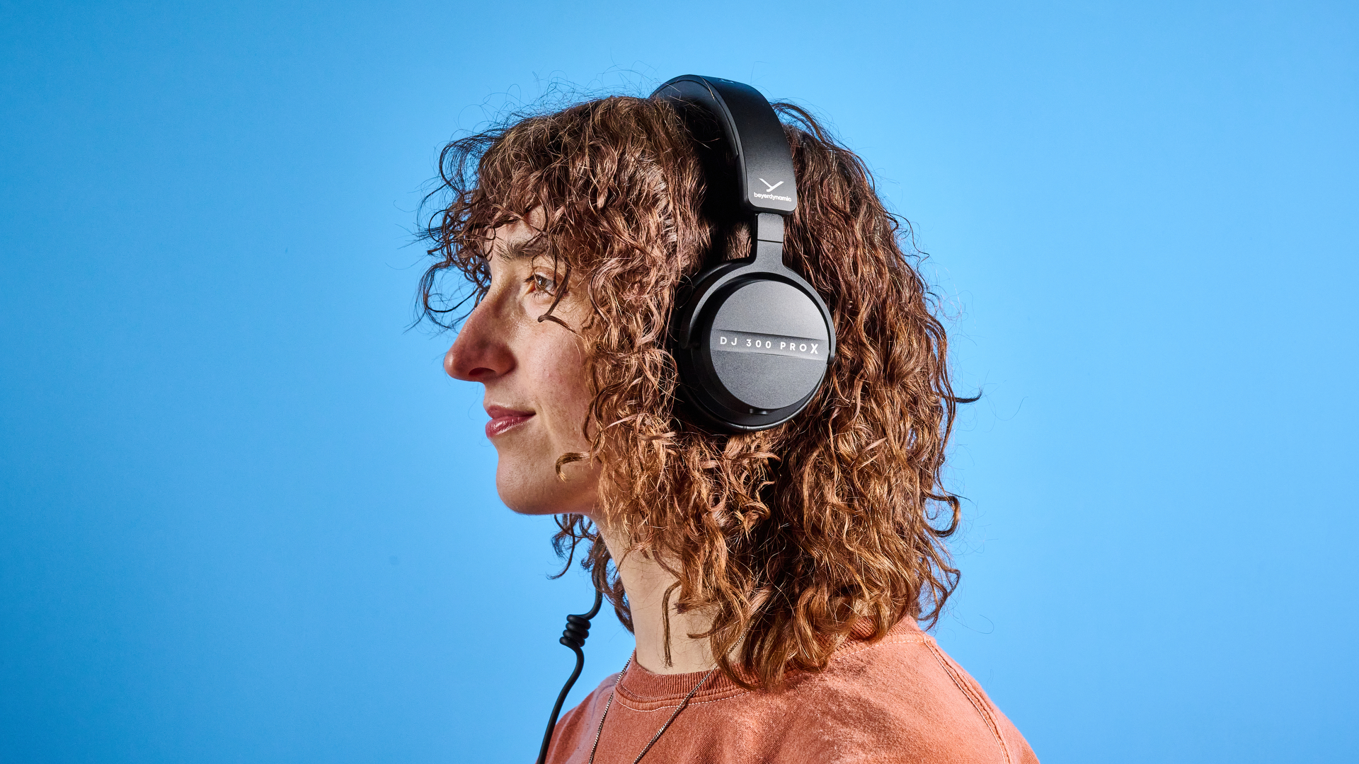 the beyerdynamic DJ 300 Pro X headphones in black showing their ear cups, carry bag, and connectivity options photographed against the blue tom's guide background