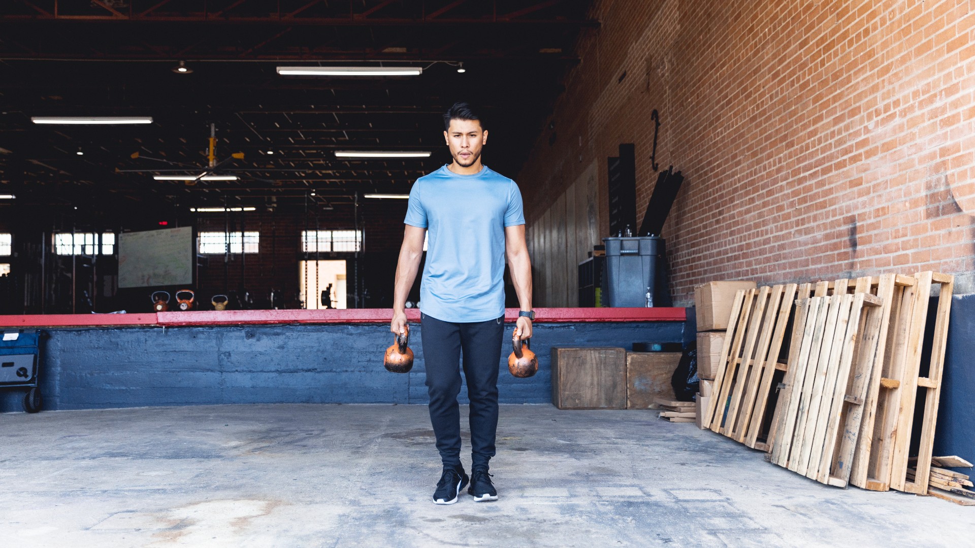 A man holding two kettlebells in each hand and doing a farmer's hold