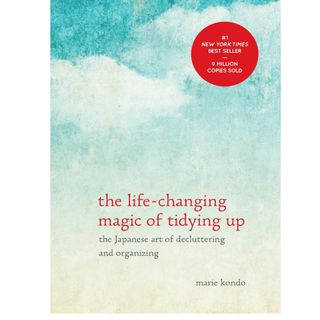 the front cover of life changing magic of tidying up book by marie kondo with a watercolor sky background and red lower case writing