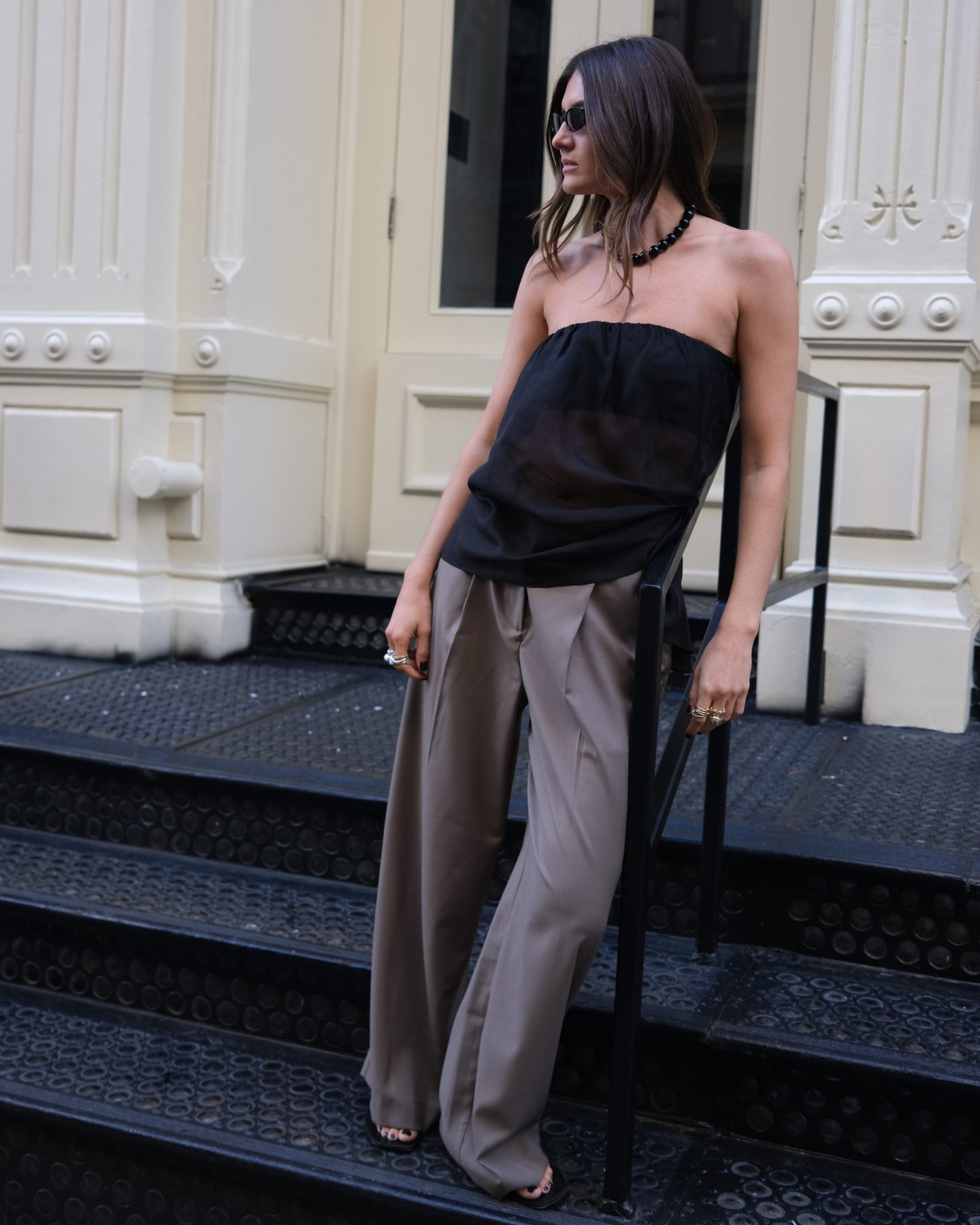 An image of @cocoschiffer wearing a black bustier with khaki pleated trousers.