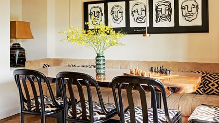 dining area with wooden table, black chairs with batik upholstery, corduroy bench, monochrome gallery wall and small brass pendant lights