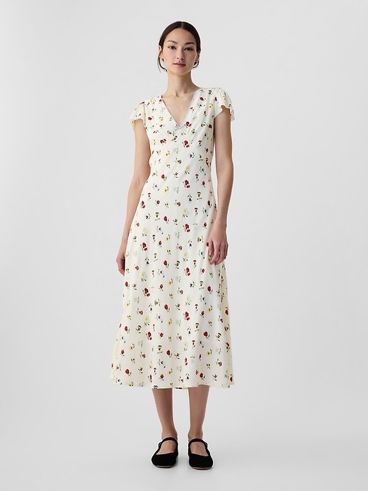 a model wears a floral white midi dress with short sleeves