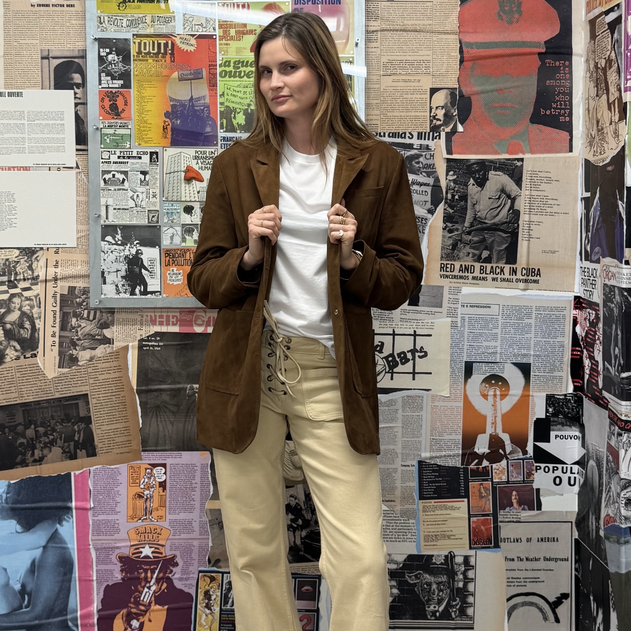 French writer and editor Eugenie Trochu poses in a brown leather suede blazer, white tee, and lace-up tan jeans
