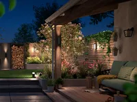wall lights in a modern garden with an outdoor sofa, decking and panelled fences