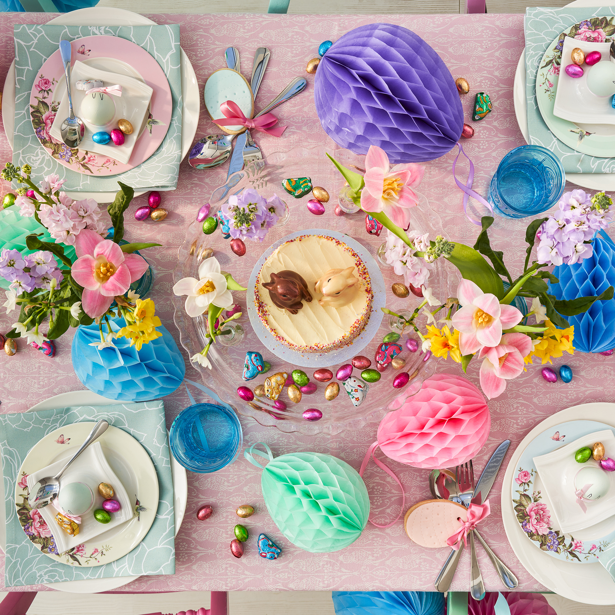 Overhead shot of a table decorated for easter with a pink tablecloth and colourful decorations