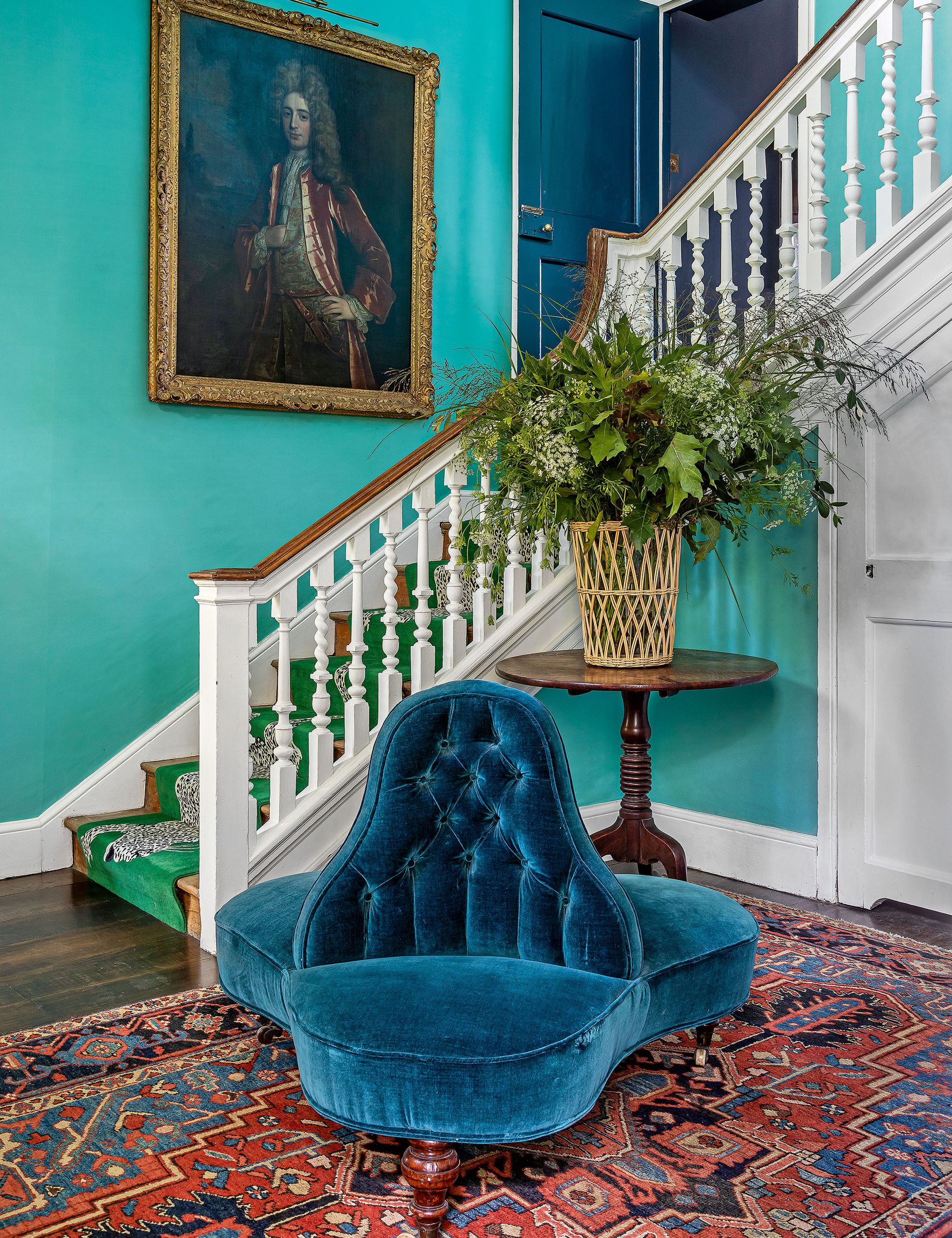 Blue hallway with red pattern rug, antique chair and table