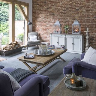 A modern country living room with an exposed brick wall and purple sofas