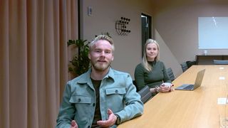 A man and woman in a conference room using Huddly cameras with AI tracking.