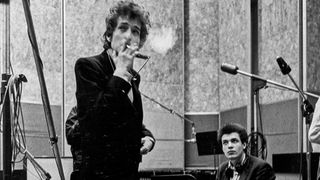 Bob Dylan (holding a cigarette) and guitarist Mike Bloomfield (seated) take a break during the recording of the album 'Highway 61 Revisited' surrounded by an assortment of microphones, amplifiers and guitars in Columbia's Studio A in the summer of 1965 in New York City, New York. 
