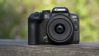 The Canon EOS R10 camera sitting on a wooden bench