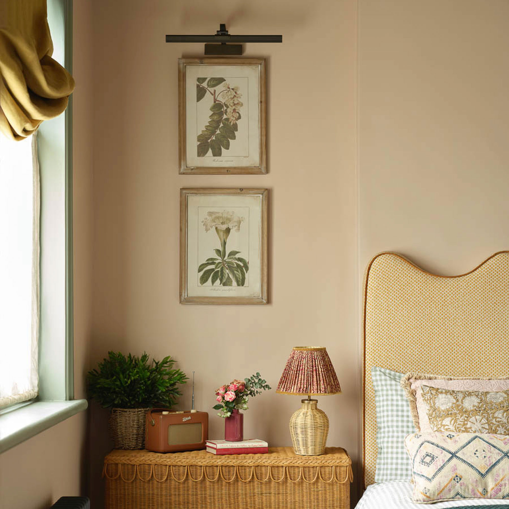 Pink bedroom with yellow headboard, two frames, rattan sideboard