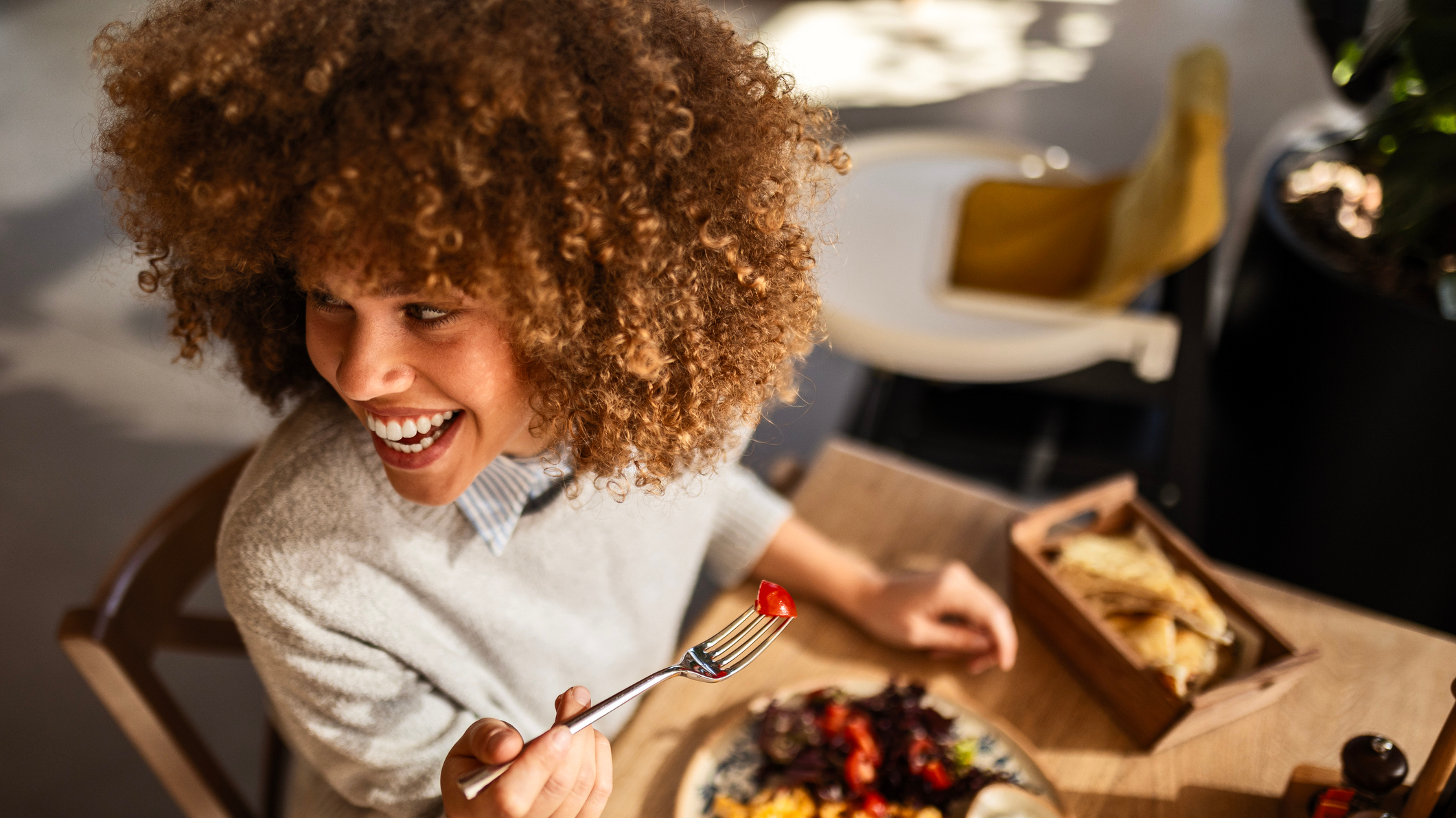 Smiling woman eating breakfast looks over her shoulder