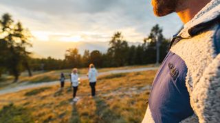 Close up of hiker's fleece in foreground with other hikers in distance at sunset