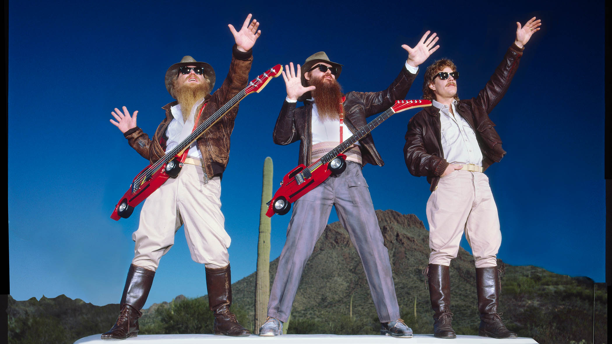ZZ Top in 1985, standing on top of a limo with their Wayne Charvel custom guitars