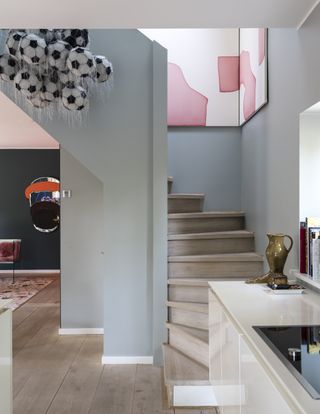 staircase with light blue walls, white trim, corner artwork and console table with decor