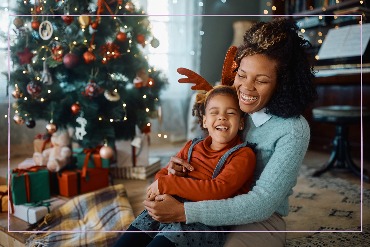 Happy African American mother and daughter having fun and laughing while celebrating Christmas at home.