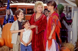 a group of children and their grandmother stand in halloween costumes in halloweentown