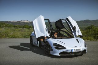 A white McLaren parked at an angle with the car doors opened.