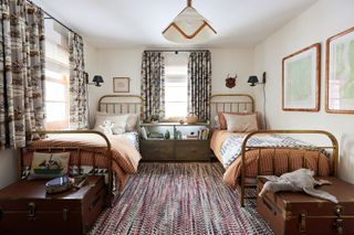 childs room with metal framed twin beds horse print curtains matching bedside tables and antique trunks and rag rug