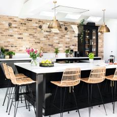 kitchen island with black units, white top and rattan stools