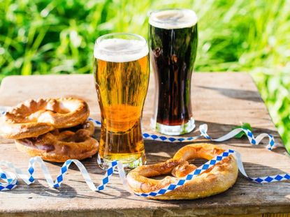 Two pints of beer and pretzels with ribbons on an outdoor table