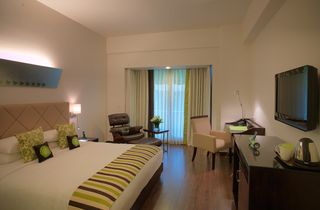 Peppermint hotel room with balcony, white bedding with lime green and brown cushions and throw