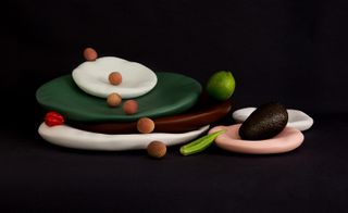 Ceramic plates in different sizes and colors, with fruit on them. Taken on a black background.