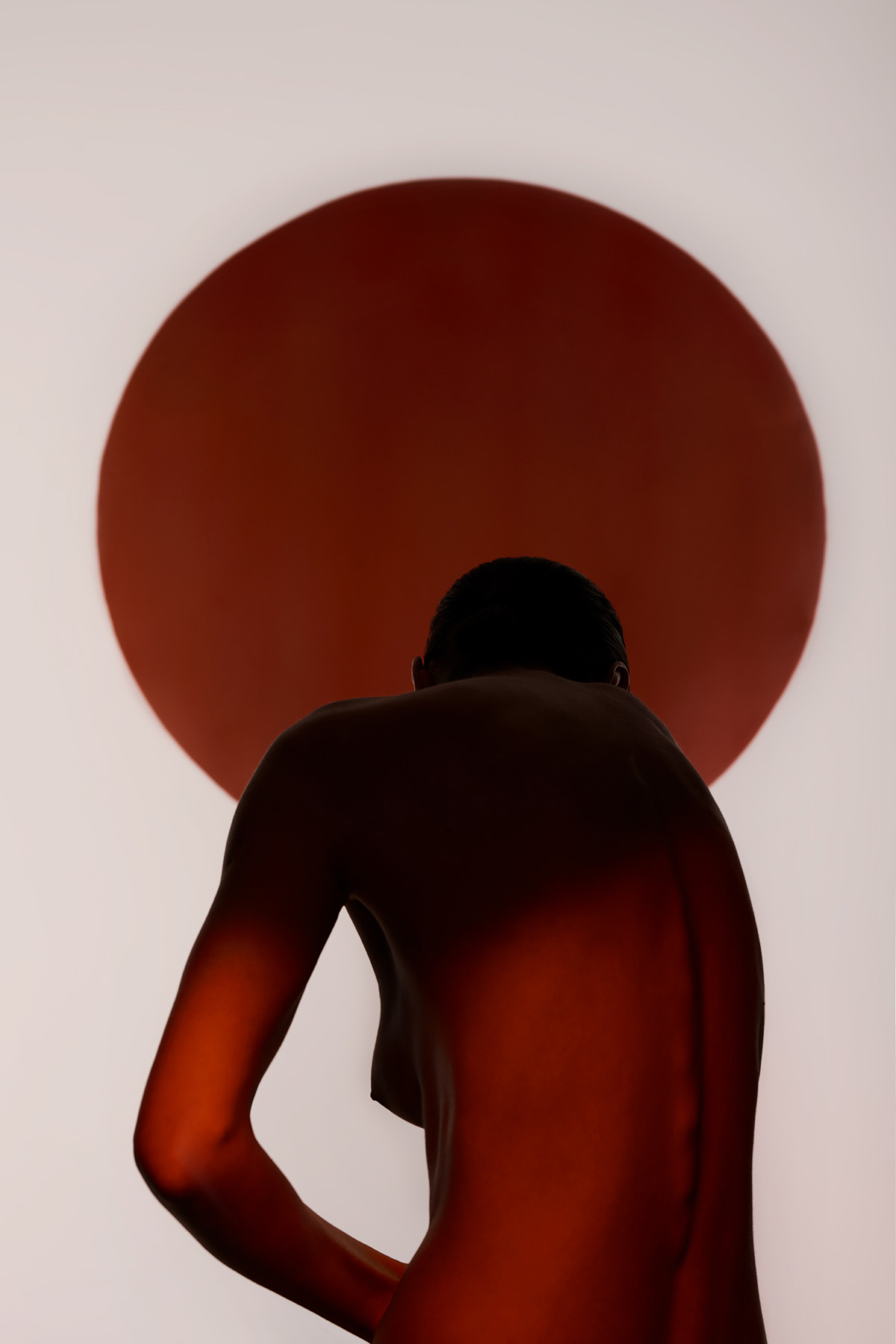 xxWoman standing in shadow in front of red and black circles