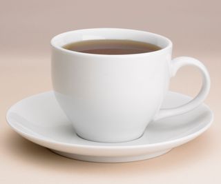 A teacup and saucer on a pale pink surface