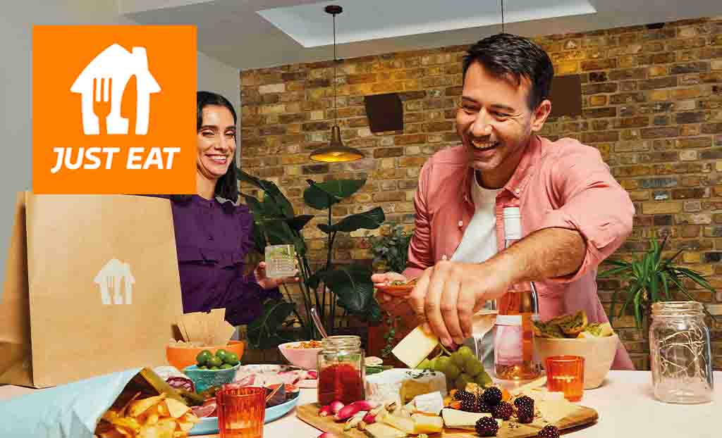 Just eat logo placed over two people unpacking food on the counter